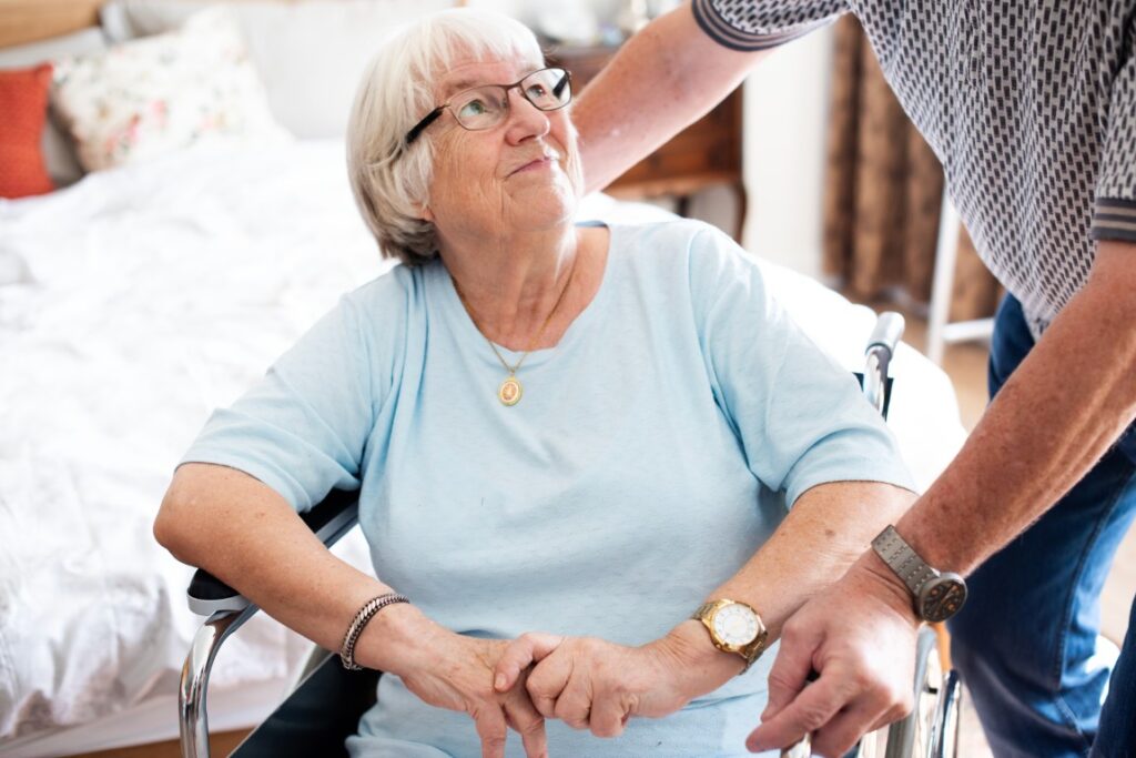 Elderly woman wheelchair assisted by man bedroom care support man assist elderly woman wheelchair home happy elderly woman with man help support elderly nursing home care