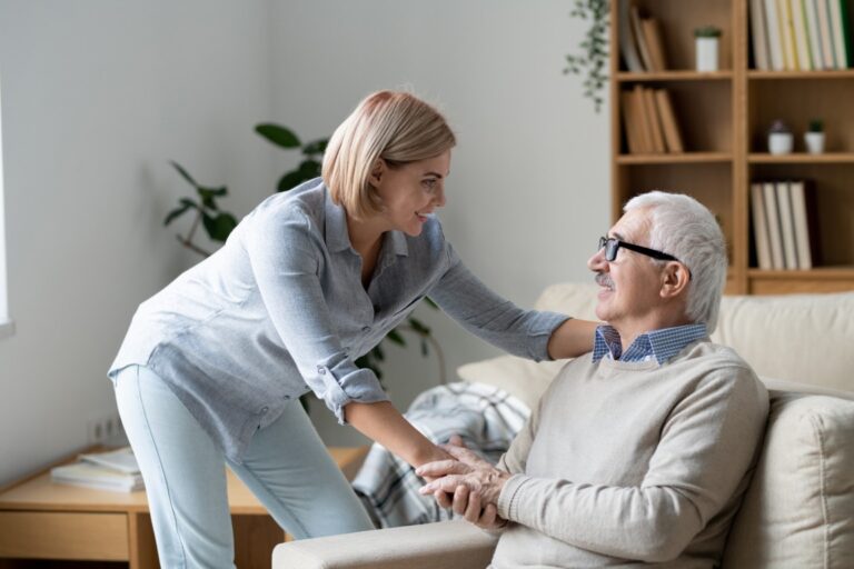 Mature man on couch holding hand of daughter while looking at her during chat