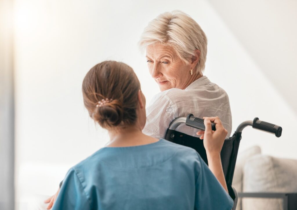 Old woman wheelchair help caregiver talking healthcare support nursing home back view happy nurse speaking senior patient elderly person with disability empathy hope